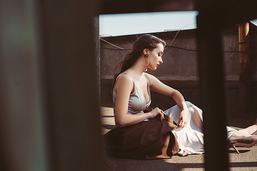 attractive elegant woman posing in silk dress and brown jacket on roof