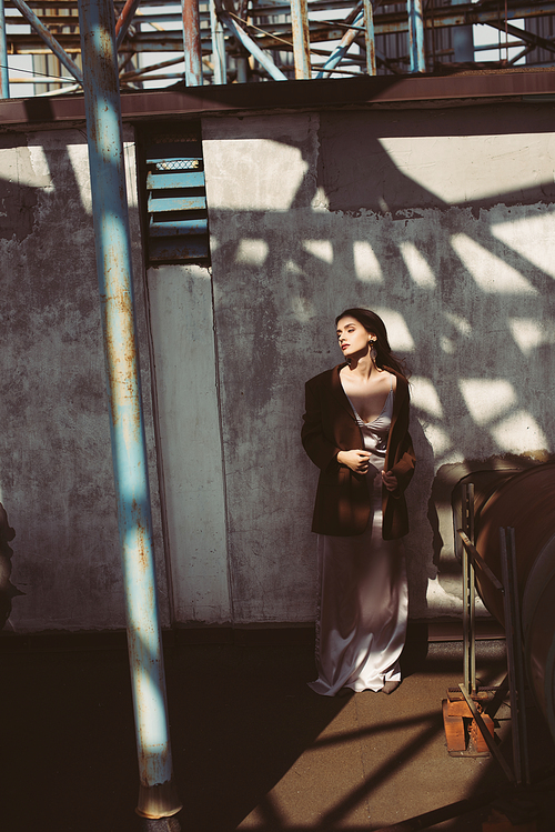 attractive woman posing in silk dress and brown jacket on roof