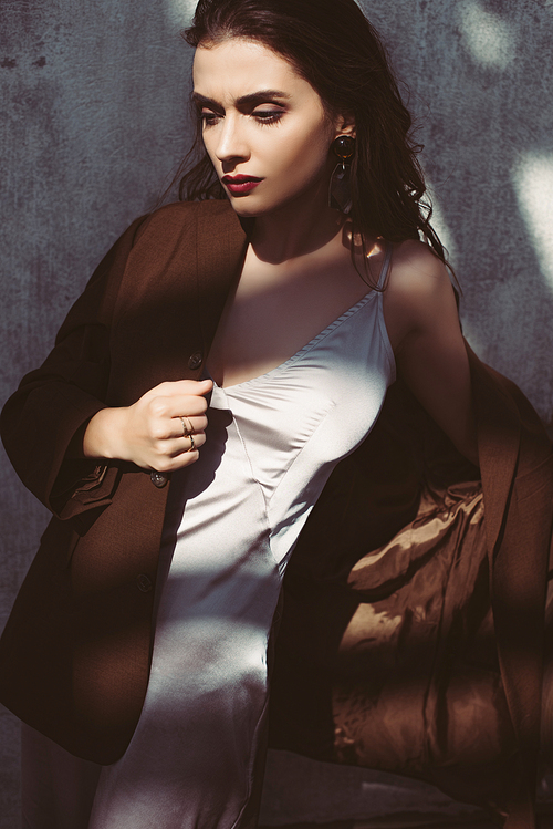 elegant trendy model posing in silk dress and brown jacket on roof