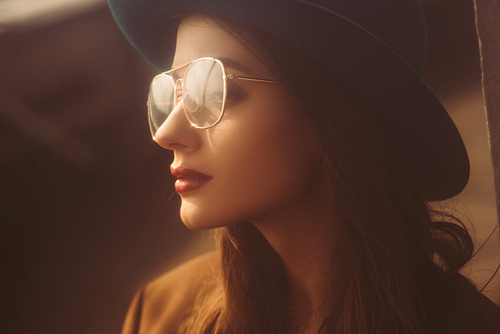 beautiful retro girl posing in eyeglasses and hat on urban roof