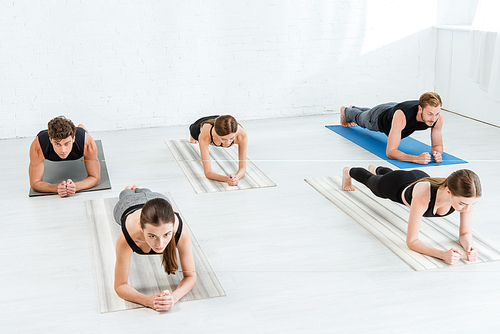 five young people practicing yoga in forearm plank pose