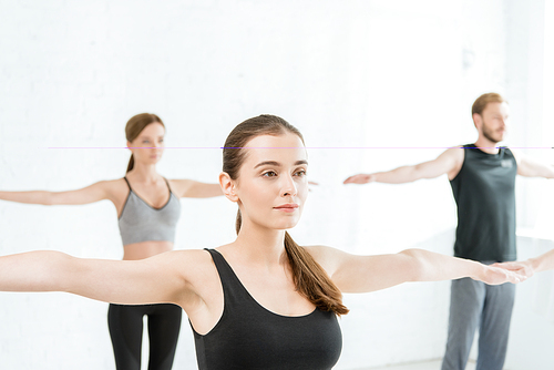 young women and man practicing yoga in mountain open arm pose