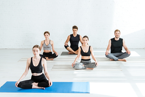 five young people practicing yoga in half lotus pose