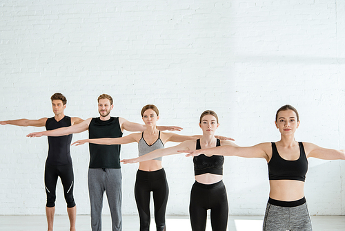 five young men and women practicing yoga in mountain open arm pose