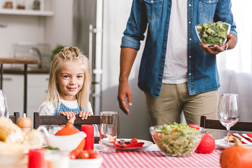cropped view of father holding bowl with broccoli and cute daughter smiling and  in Thanksgiving day