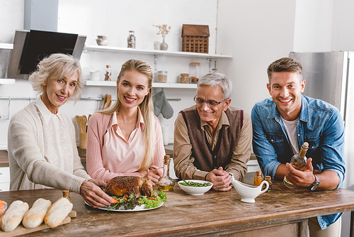 smiling family members holding plate with turkey and  in Thanksgiving day