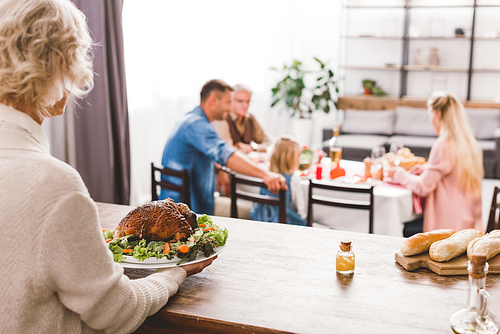 selective focus of grandmother holding plate with tasty turkey in Thanksgiving day