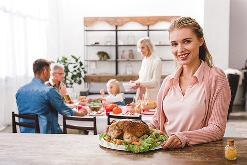 smiling mother holding plate with tasty turkey in Thanksgiving day