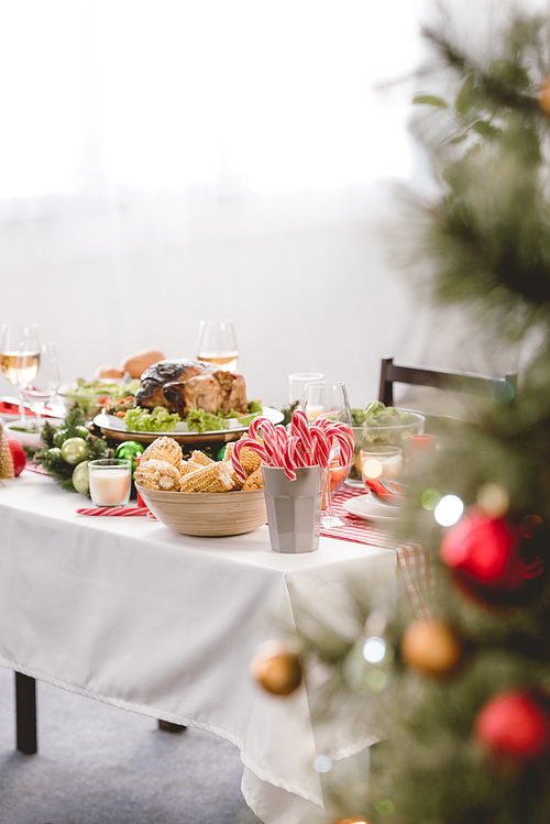 selective focus of plate with tasty turkey, corn, sweets and wine glasses on table in christmas