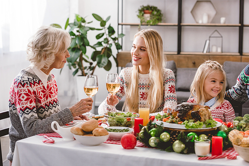 family members sitting at table and holding wine glasses in Christmas