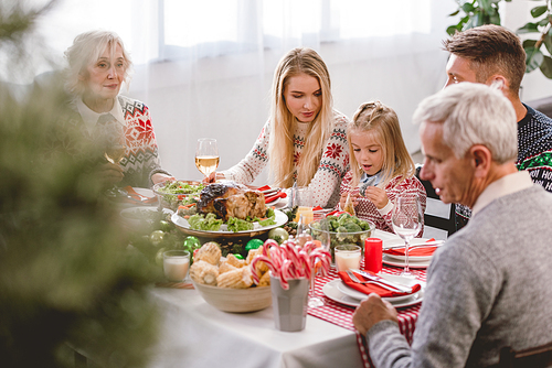 selective focus of family members sitting at table and celebrating Christmas