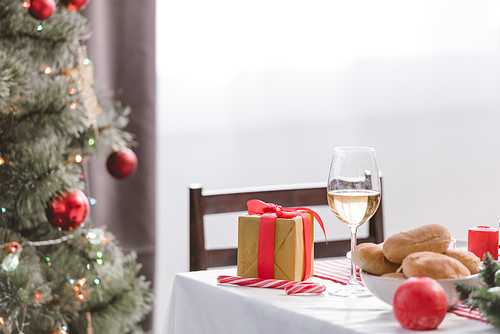 selective focus of wine glass, pies and christmas gift on table