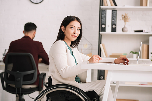 smiling disabled businesswoman  while sitting in wheelchair at workplace
