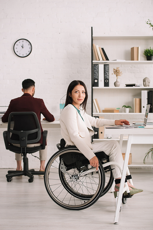 beautiful disabled businesswoman  while sitting in wheelchair near colleague