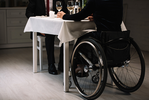cropped view of young woman in wheelchair having romantic dinner with boyfriend