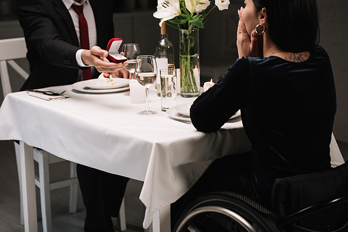cropped view of young man making wedding proposal to disabled girlfriend while having romantic dinner