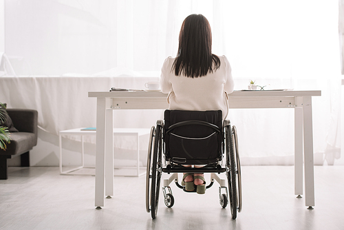 back view of businesswoman sitting in wheelchair near desk in office