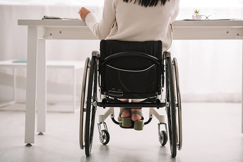 back view of disabled businesswoman sitting in wheelchair at workplace