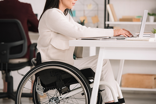cropped view of disabled businesswoman sitting in wheelchair at workplace