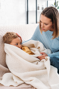 caring mother looking at diseased son wrapped in blanket