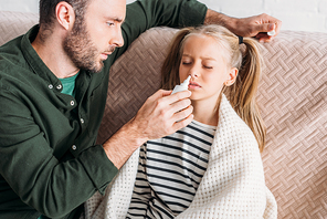 caring father holding nasal spray near diseased daughter