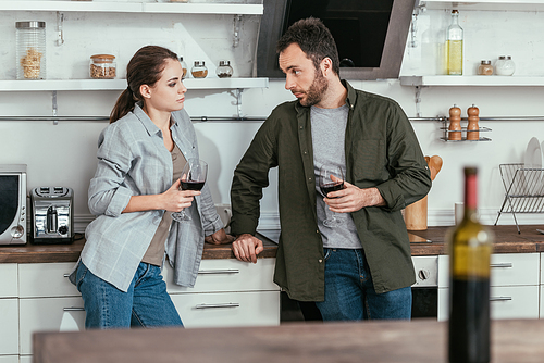 Selective focus of couple holding glasses of wine on kitchen