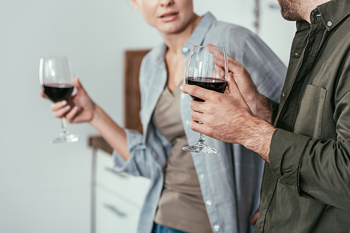 Cropped view of couple with wine glasses talking on kitchen