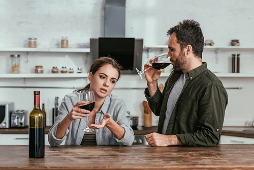 Alcohol addicted couple drinking wine and talking on kitchen