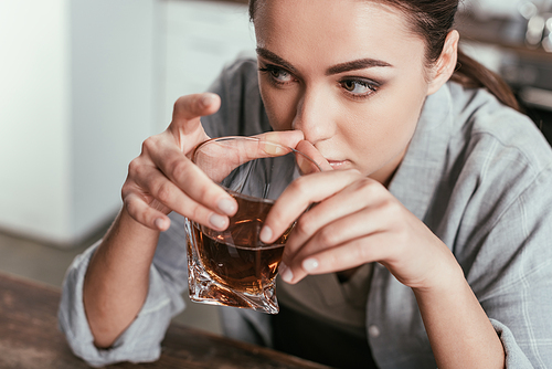 High angle view of woman holding whiskey glass and looking away