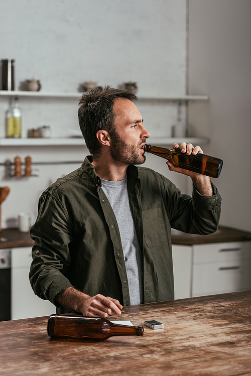 Alcohol addicted man drinking beer at kitchen