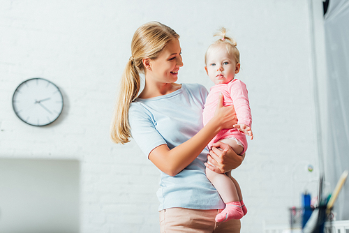 Selective focus of woman holding baby girl at home