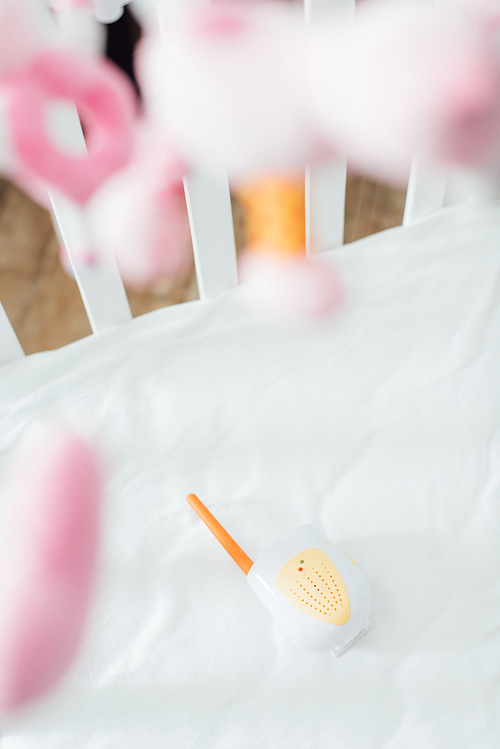 Selective focus of baby monitor in crib with soft toys