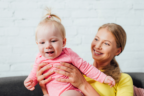 Selective focus of mother carrying baby daughter at home