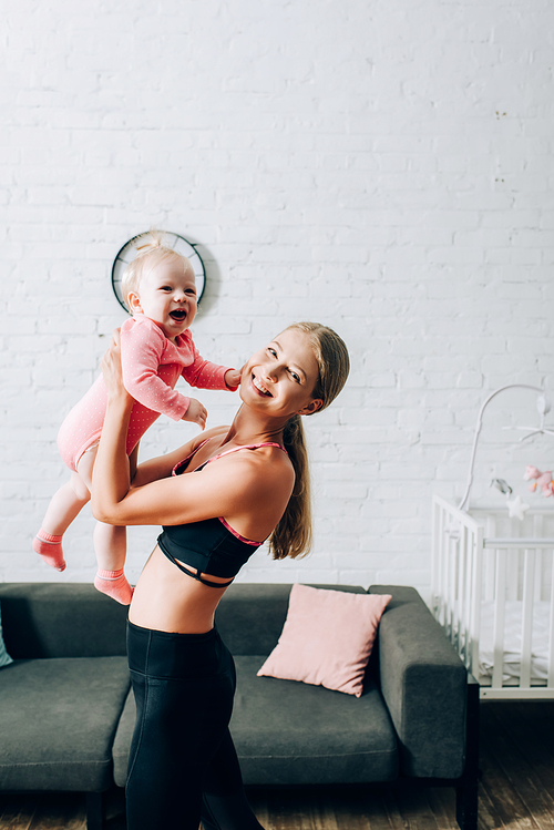 Woman in sportswear  while holding daughter in living room