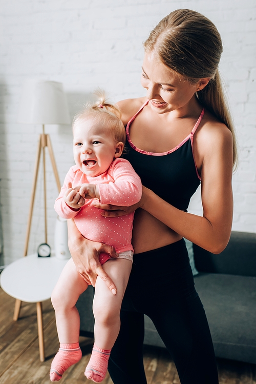 Fit woman holding baby daughter in living room