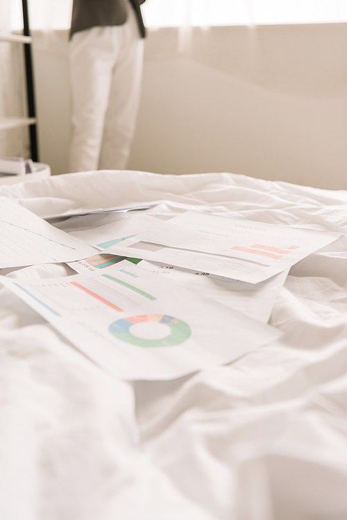 cropped view of freelancer and papers with graphs and charts on white bedding