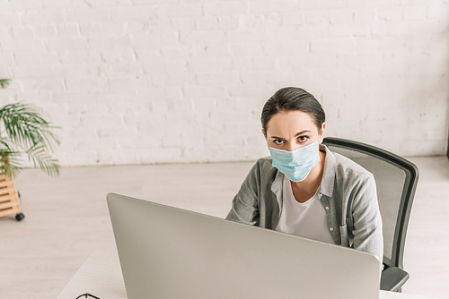 high angle view of freelancer in medical mask  while working at home