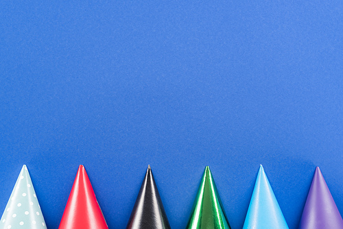 Top view of multicolored party hats on blue background