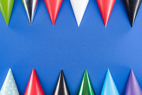 Colorful birthday hats on blue background with copy space