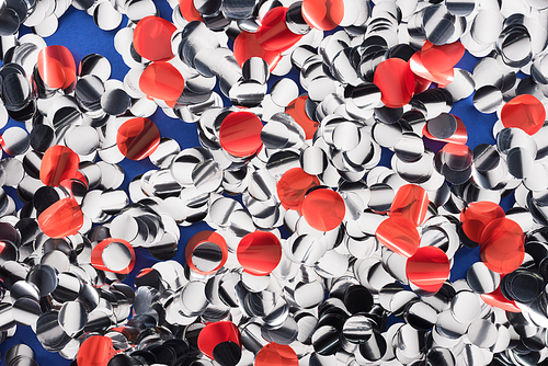 Top view of abstract silver and red confetti on blue background