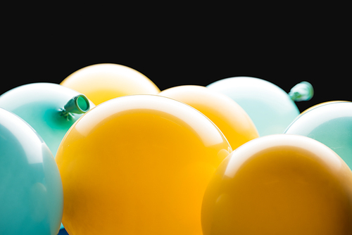 Close up view of yellow and blue balloons isolated on black