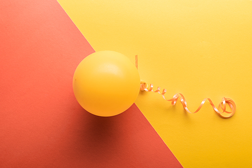 Top view of yellow balloon on coral and yellow background