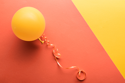 Top view of yellow balloon on coral background