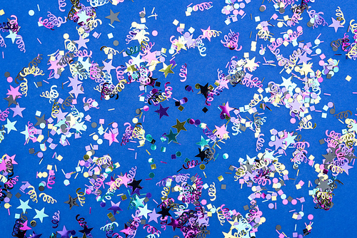 Top view of colorful sparkling confetti on blue background