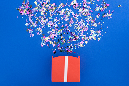 Top view of gift box with shiny bright confetti on blue background