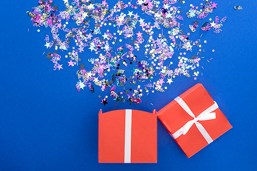 red gift box and multicolored shiny confetti on blue background