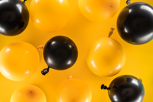Top view of yellow and black balloons on bright background
