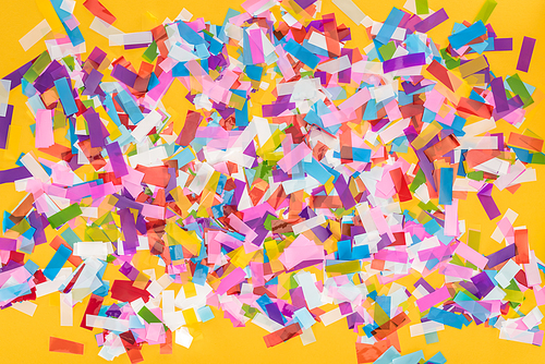 Top view of colorful confetti on yellow party background