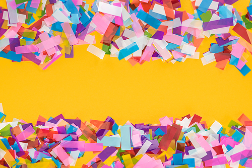 Top view of multicolored confetti frame on yellow background