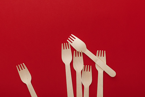 top view of natural wooden forks on red background with copy space